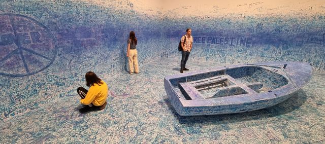a man and two children in a room covered in blue graffiti with a boat on the floor